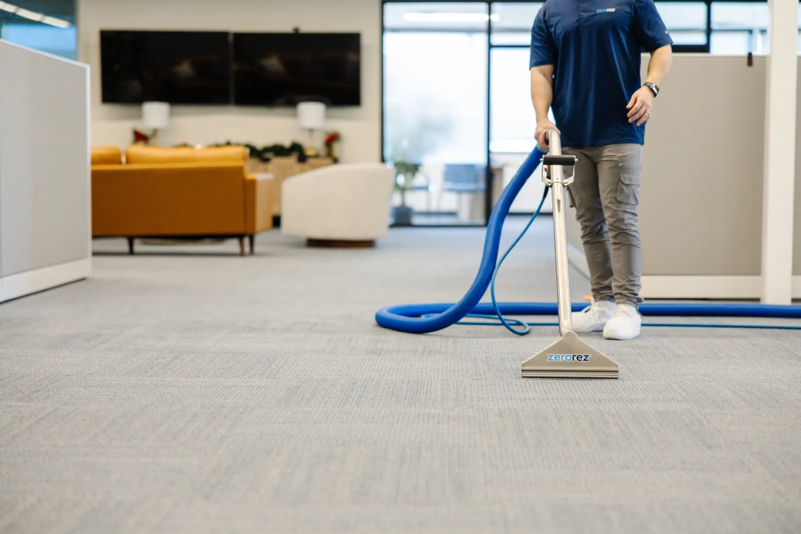 technician in an office cleaning the carpet with a wand
